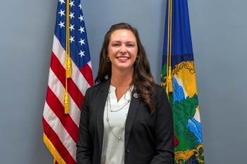 Former Vermont Emergency Management Director Erica Bornemann posing in front of the Vermont and U.S. flags