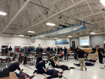Simulated victims being attended to by emergency responders on a gym floor. This is simulated and part of an exercise.