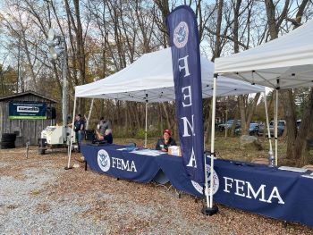 FEMA Staff sitting behind a table under a tent